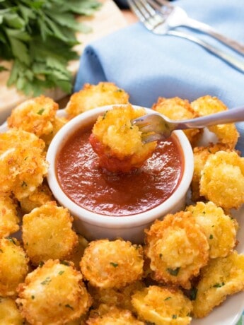 Parmesan Crusted Tortellini Bites with a fork dipping one into Marinara sauce.