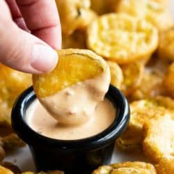 A labeled image of a hand dipping a fried pickle into sauce.