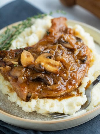 French Onion Smothered Pork Chops on a pile of mashed potatoes.
