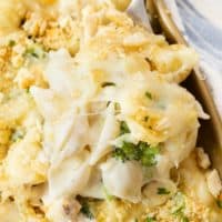 A big scoop of chicken Alfredo bake being scooped from a casserole dish.