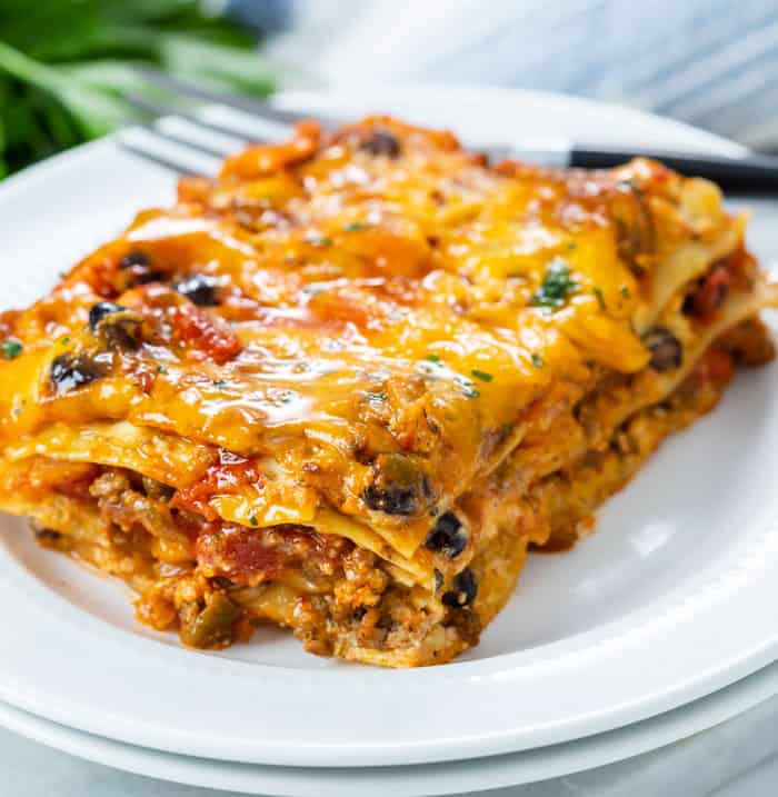 A white plate with a slice of taco lasagna on it.