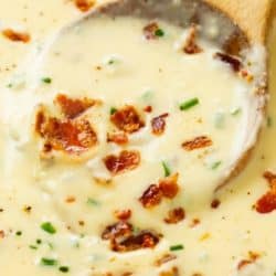 A wooden ladle scooping up Baked Potato Soup from a pot.