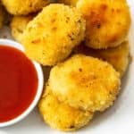 Golden Homemade Chicken Nuggets on a white plate next to sweet and sour sauce.