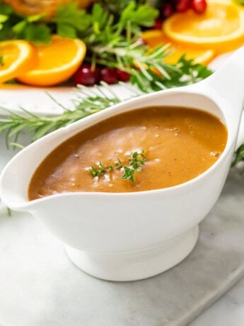 Thick brown turkey gravy in a gravy boat topped with fresh thyme.
