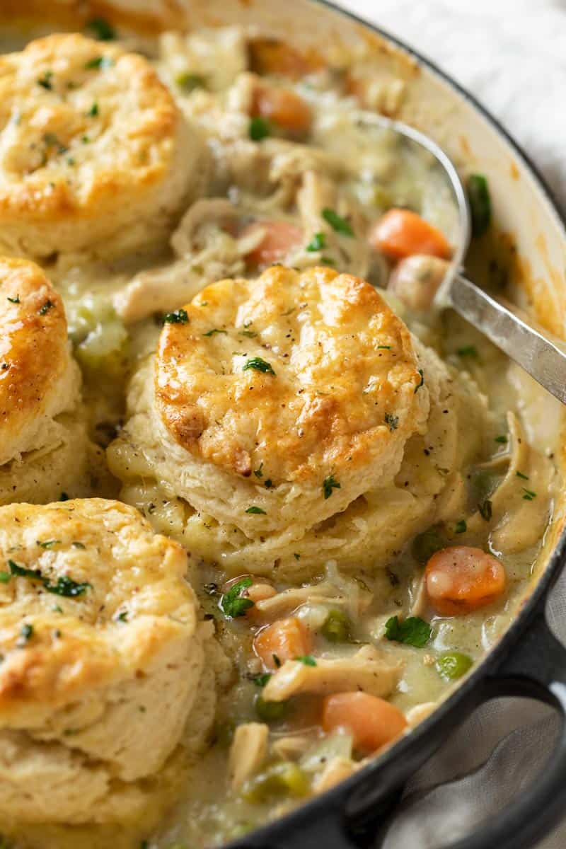 A golden biscuit on top of a skillet filled with chicken pot pie.