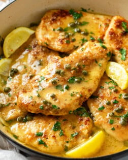 A pot with crispy Chicken Piccata in a white wine butter sauce with lemon wedges and capers.