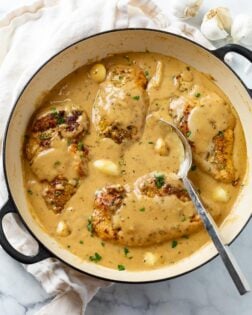 A skillet filled with Creamy Garlic Chicken in a sauce with whole garlic cloves.