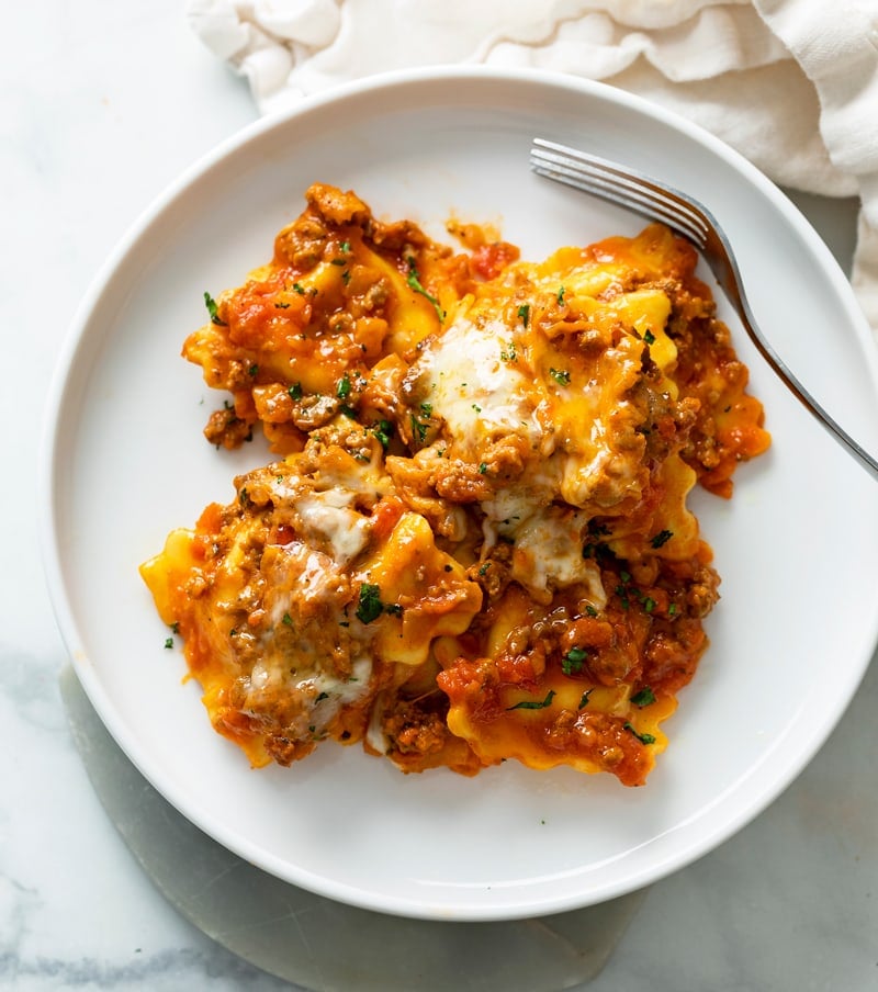 A white plate with Baked Ravioli with a fork on the side.