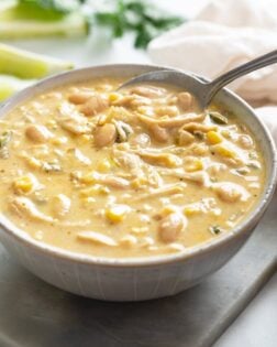 A bowl with a spoon scooping up white chicken chili.