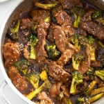 A skillet with Beef and Broccoli topped with sesame seeds.