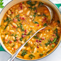 A Dutch oven filled with white bean soup with a ladle in it.