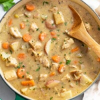 Chicken Stew in a soup pot with a wooden spoon on the side.