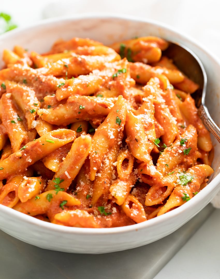 Penne Alla Vodka in a White Bowl with a spoon on the side.
