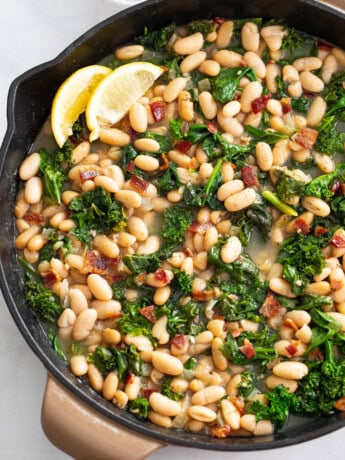 Greens and Beans in a skillet with bacon and freshly sliced lemon.