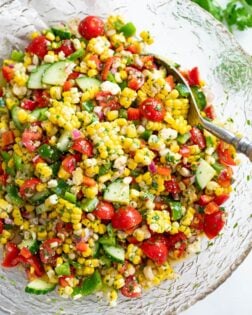 Overhead view of Corn Salad in a glass bowl with a spoon on the side.