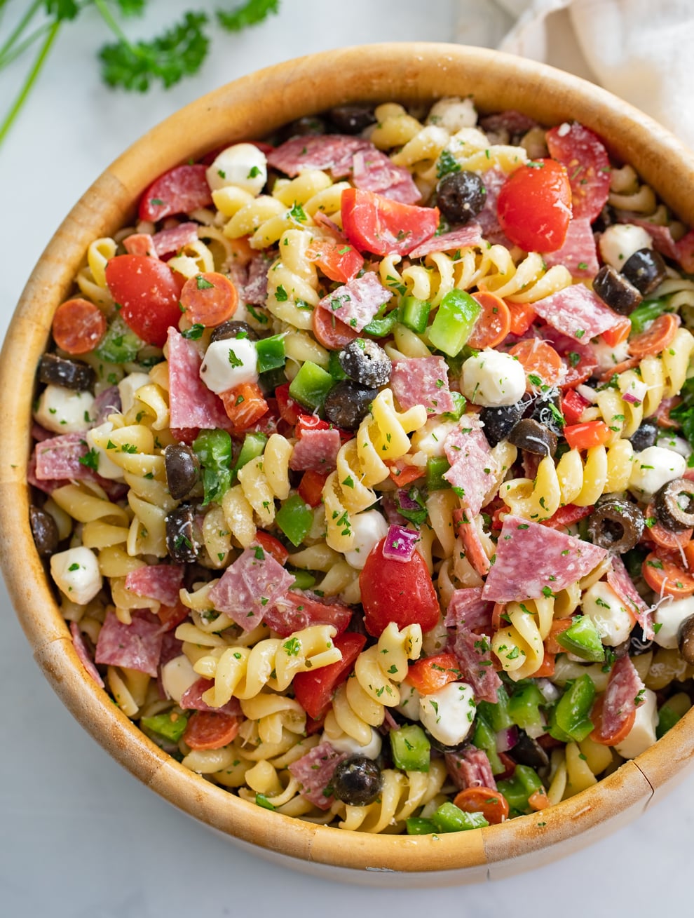 Italian Pasta Salad in a wooden bowl with Rotini Pasta, Salami, Pepperoni, Mozzarella, and more.