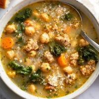 Chickpea Soup in a bowl with Parmesan cheese on top and a spoon on the side.
