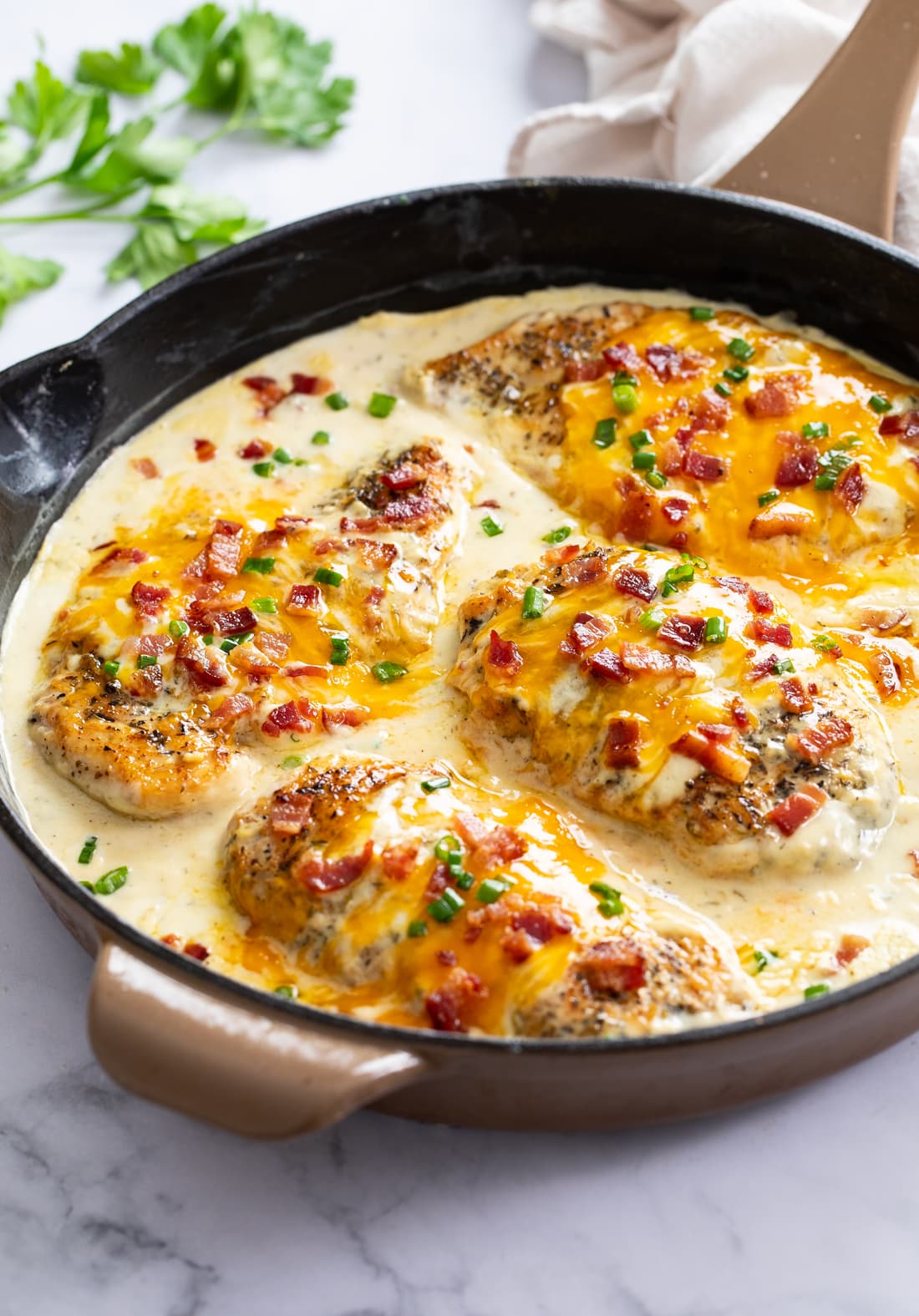 A skillet of Bacon Ranch Chicken in a ranch sauce with bacon and cheese.