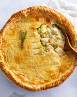 Overhead view of Chicken Pot Pie in a pie pan with a wooden spoon scooping it up.