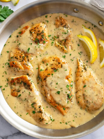 Garlic Parmesan Chicken in a skillet with sauce and fresh parsley on top.