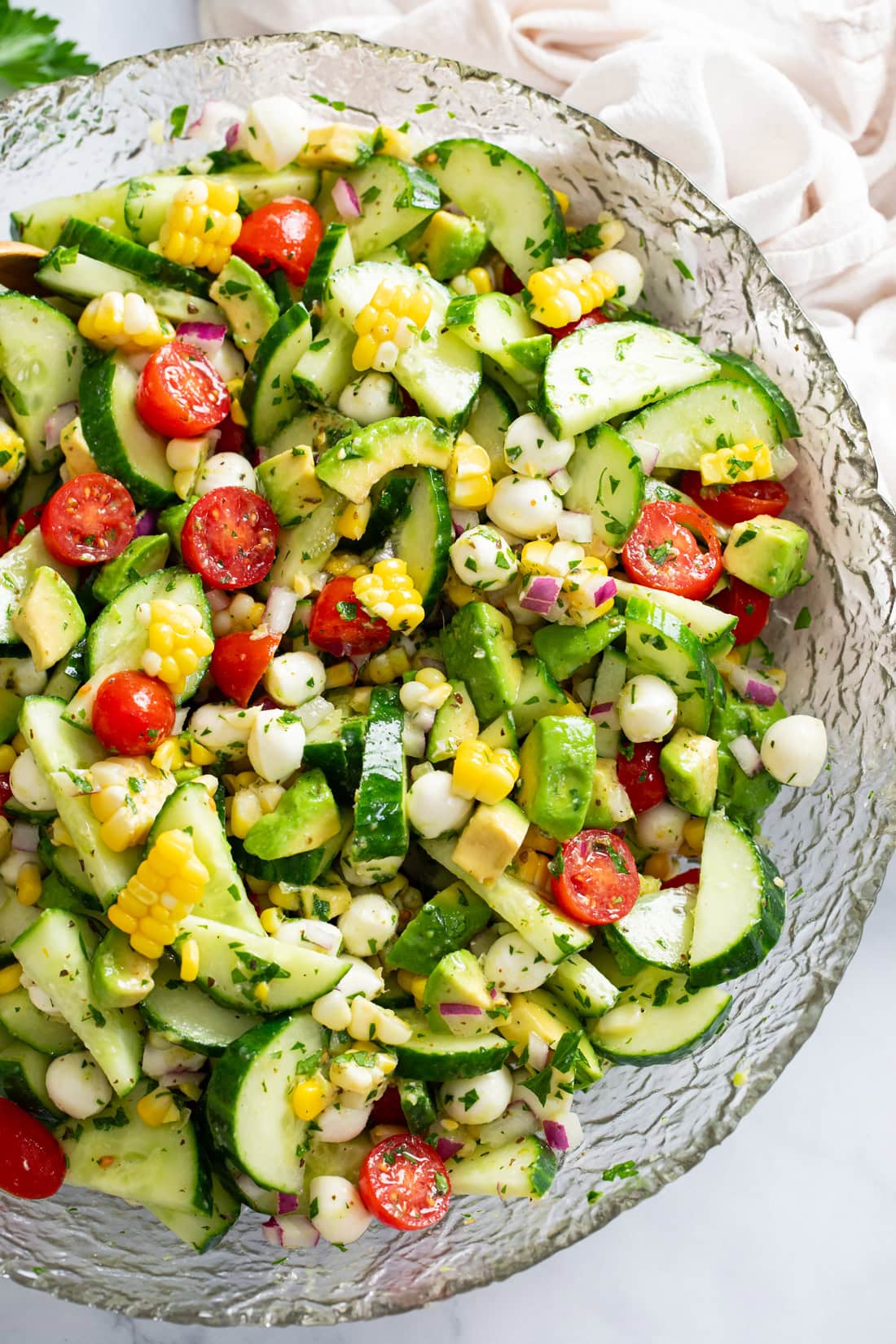 A glass bowl filled with Cucumber Avocado Salad.