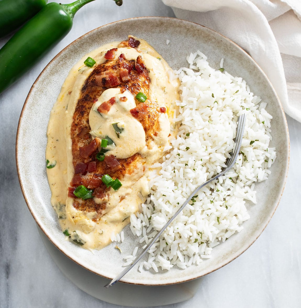 Jalapeno Popper Chicken on a plate with white rice and a fork on the side.