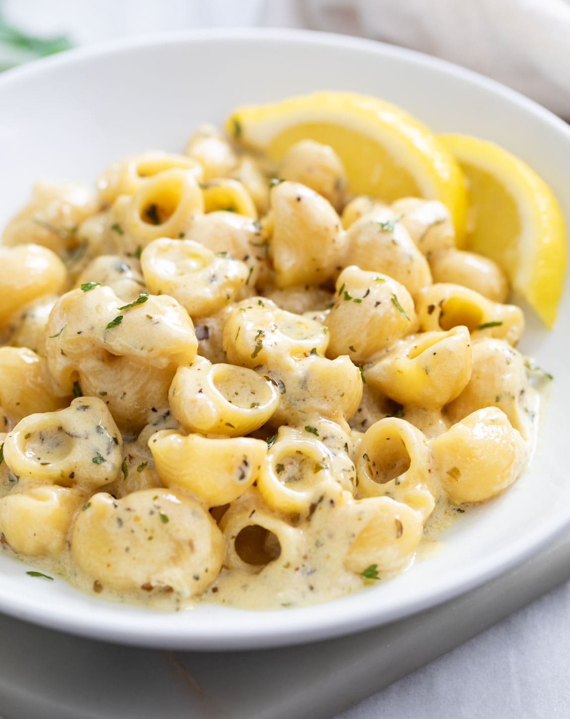 Garlic Butter Pasta on a white plate with lemon slices in the background.