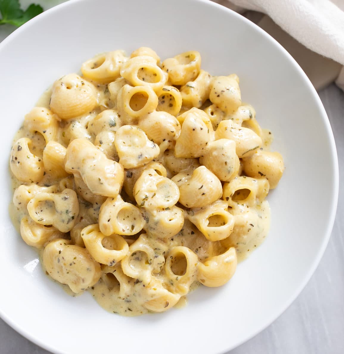 Overhead view of Garlic Butter Pasta on a white plate with parsley and herbs.