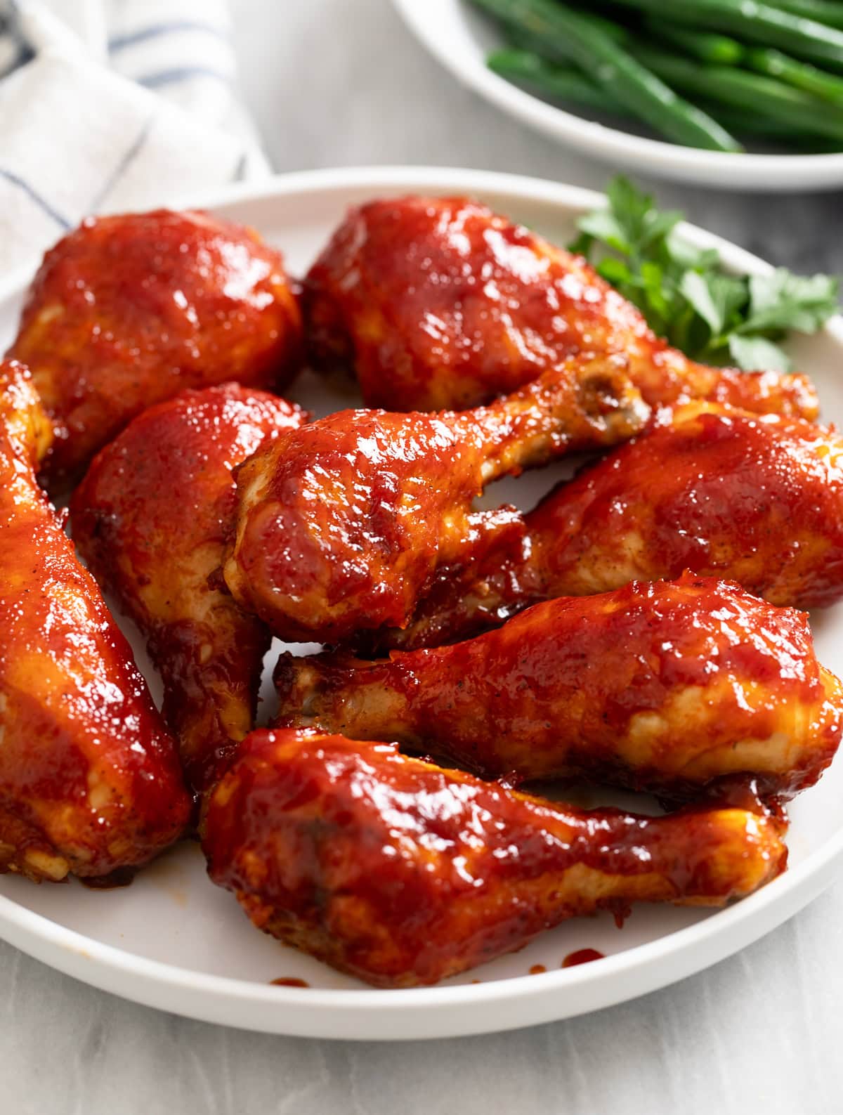 BBQ Chicken Chicken on a white plate with green beans in the background.