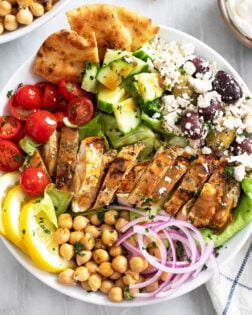 Greek Chicken Bowls with Tomatoes, Cucumbers, Chickpeas, Olives, Feta, Homemade Dressing, and more.