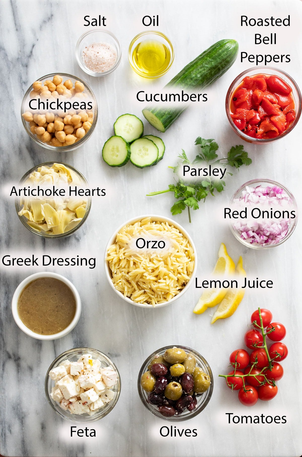 Labeled ingredients for making Orzo Salad on a white surface.