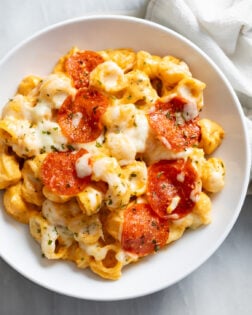 Pizza Mac and Cheese with mozzarella and pepperoni on top in a white bowl.